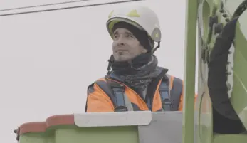 témoignage pénibilité Bertrand, monteur électricien installé dans sa nacelle en hauteur près d'un poteau électrique, il porte son équipement de sécurité dont casque
