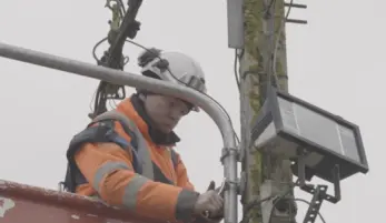 monteur électricien dans une nacelle, travaillant sur un poteau électrique, avec son équipement de sécurité dont casque