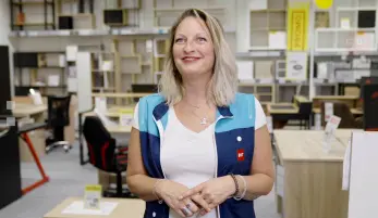 Orianne vendeuse polyvalente chez BUT, avec son gilet/chasuble du magasin, sur son lieu de travail